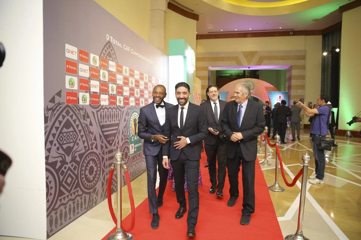 QNET sponsored event in CAF, people in suits walking along the red carpet. 