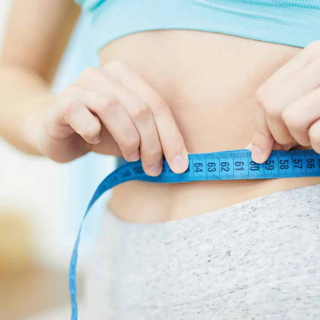 Woman measuring her waist with blue measuring tape