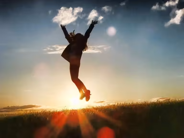 Silhouette of a person jumping over a horizon, signifying their joy at achieving more business success by developing more future-ready skills