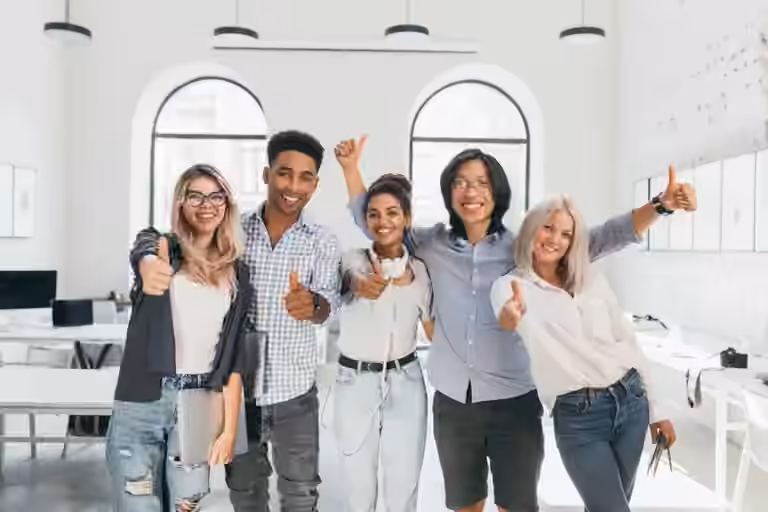 Group of young men and women in office giving thumbs up