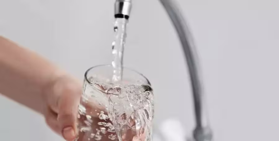 Sip By Sip: Why Clean Water Is Essential For Staying Hydrated 2 man holding glass of water under sink for QNET homepure