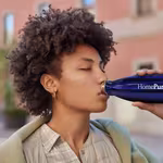 A woman drinks from her HomePure reusable bottle, advocating health, cleanliness, and sustainability through hydration.