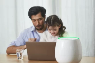A father and his daughter sit at a table with a laptop, while HomePure Zayn ensures safe and clean indoor air