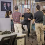 Trevor talking with QNET staff in office