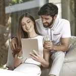 Couple looking at ipad smiling in modern home
