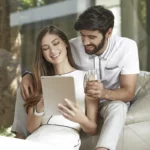 Couple looking at ipad smiling in modern home
