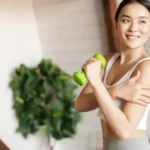 Woman exercising with a small dumbbell, reaping the benefits of a plant-based diet, which helps address climate change