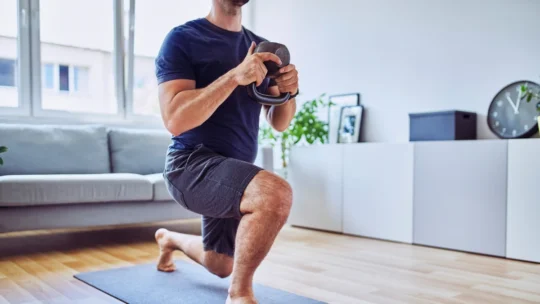 Guy working out with a kettle bell as part of his fitness resolutions to develop the healthy habits of successful people