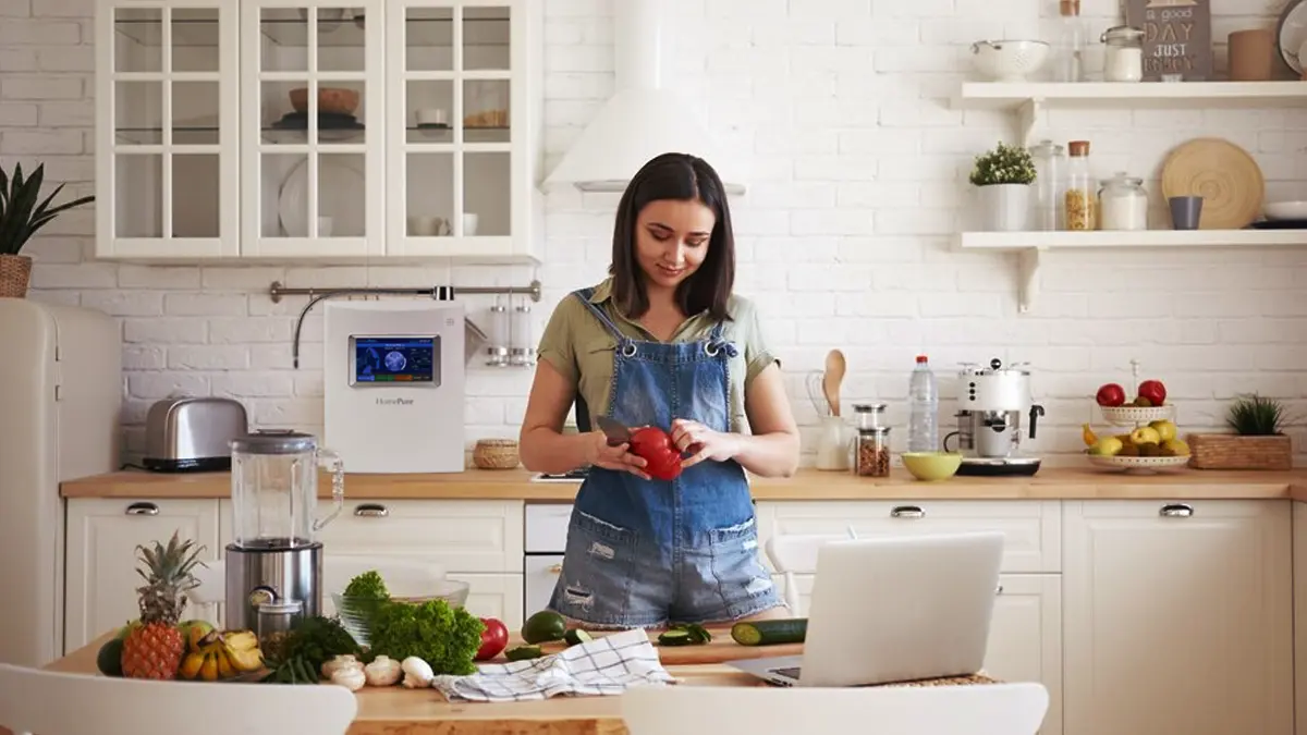 Young woman in the kitchen cutting vegetables which she prepared with the help of HomePure Viva water
