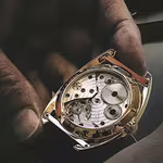 Hand holding a QNET watch with inside mechanism displayed, preparing it for repair