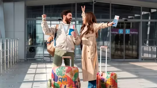 couple outside airport cheering with their luggage