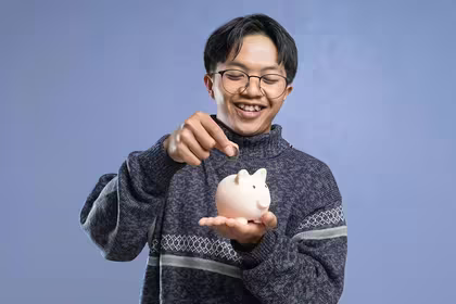Guy symbolically saving his QNET earnings in a piggy bank