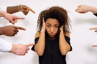 girl with hands over ears wondering how do you handle criticism symbolised by other people's hands pointing at her